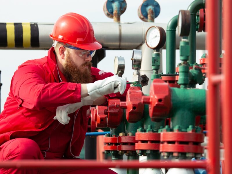 Engineer in hard hat and safety glasses checking gauges and valves on gas pipework, illustrating gas safety testing in Nottingham
