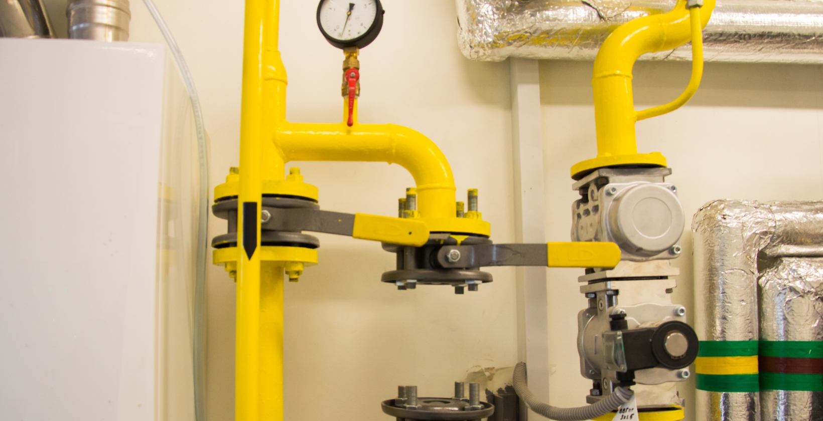 Yellow steel gas pipework with pressure gauge, flanged valves and gas train, the type of process supply we install for Derby manufacturers