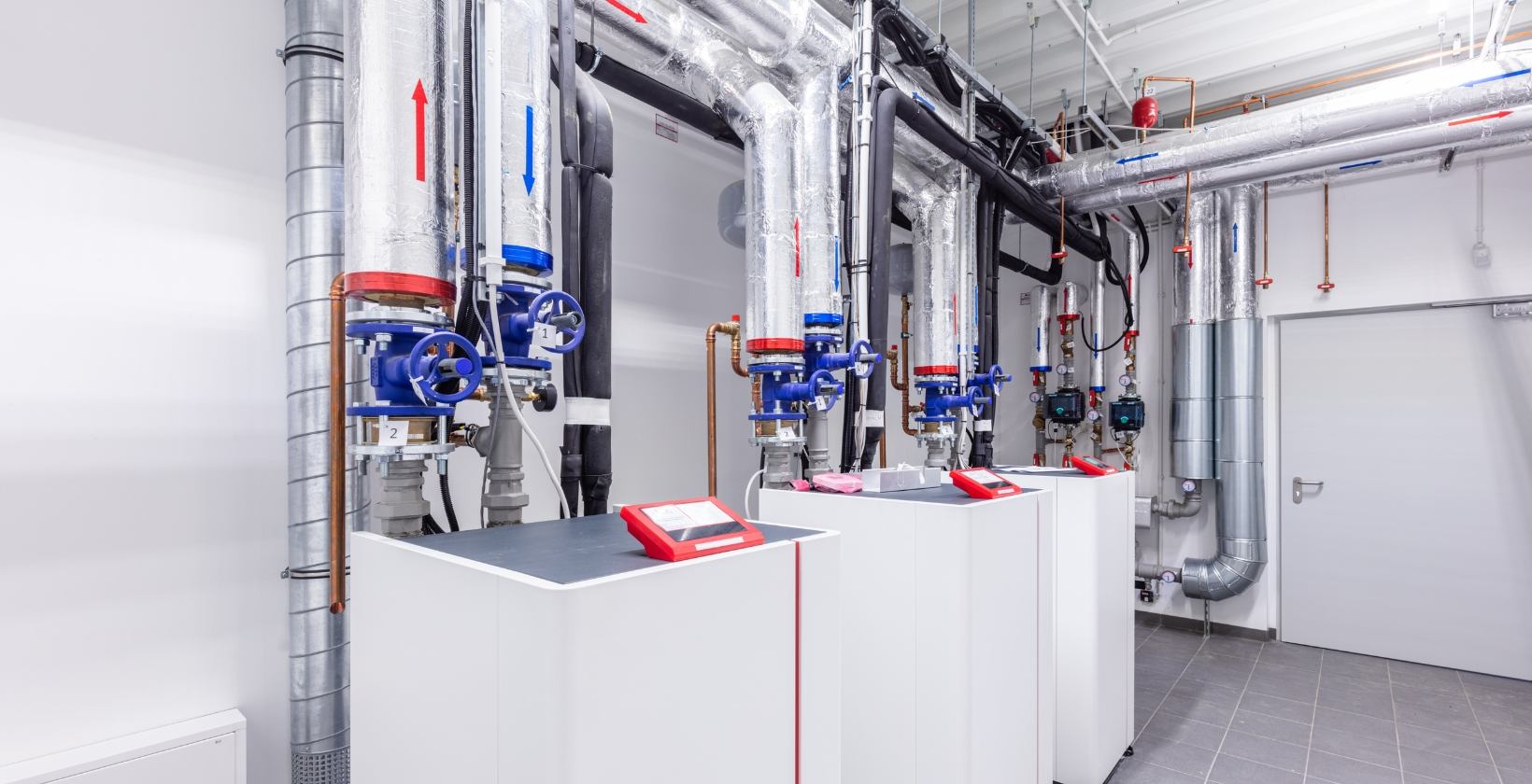 Commercial Heating Systems | Commercial Gas Pipework Commercial plant room with floor-standing boilers, insulated flow and return pipework and isolation valves